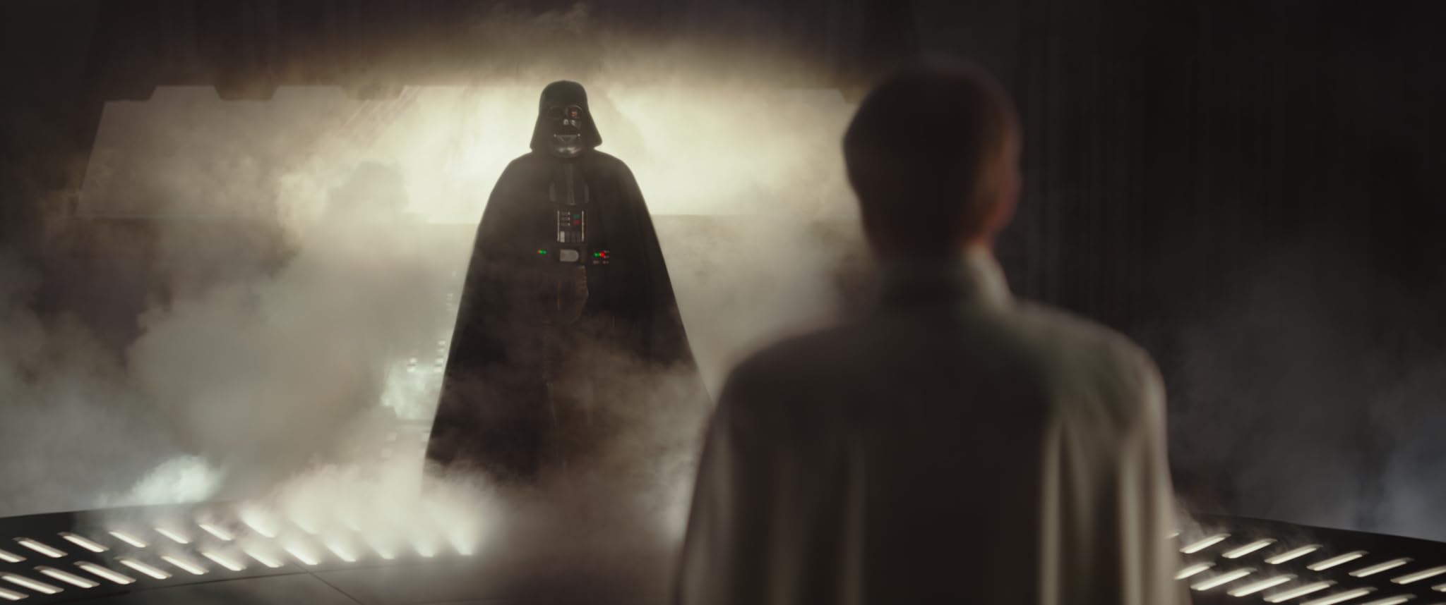 K-2SO and Chirrut ├Ämwe move through a candlelit vault while the storm outside rages.